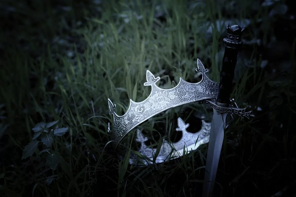 Mysterious and magical silver king crown and sword in the fields.