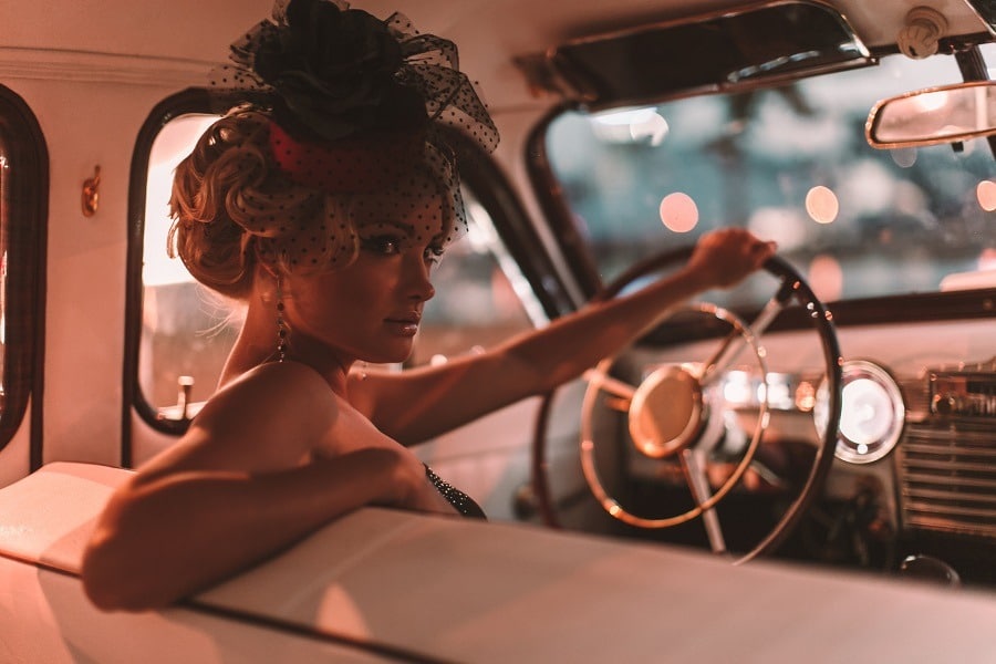 Beautiful sexy blond girl in retro style sitting in an old car.