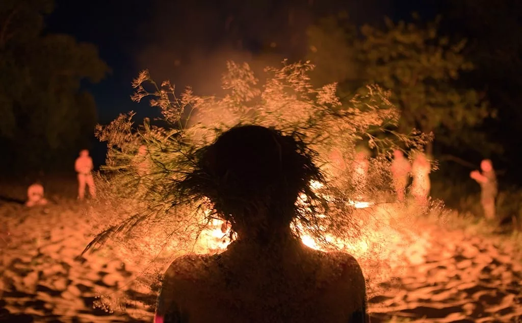 Silhouette of a woman wearing a flower crown by the fire