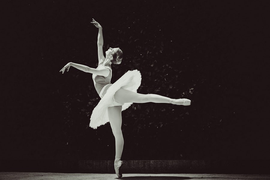 Ballerina stunning arabesque pose in black and white background.