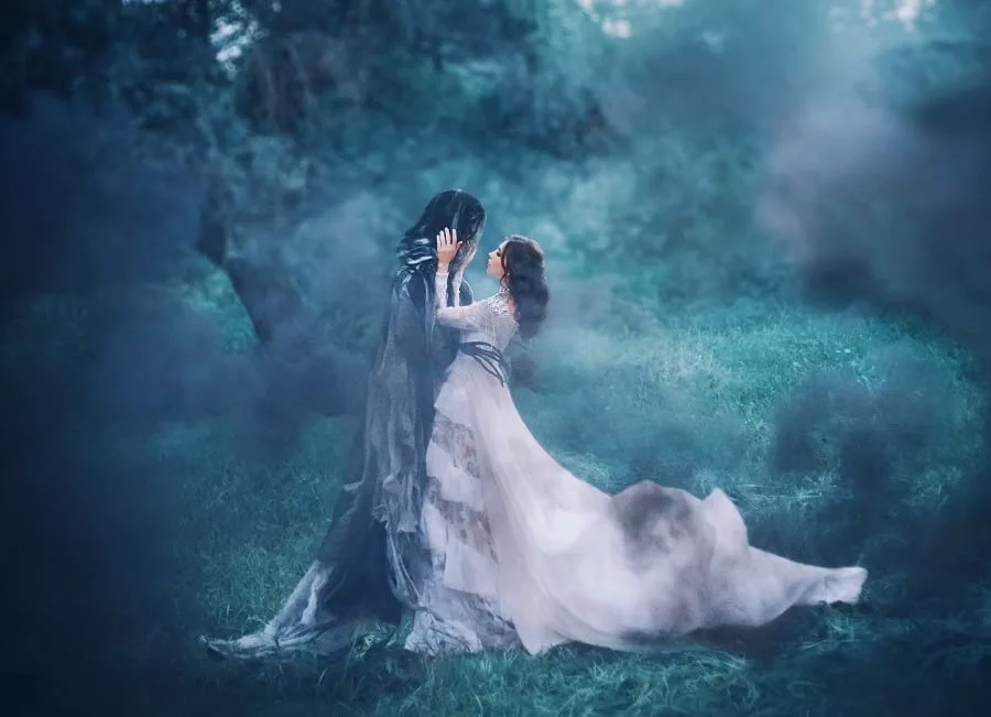 Lady in white vintage lace dress hugs lover in foggy forest.