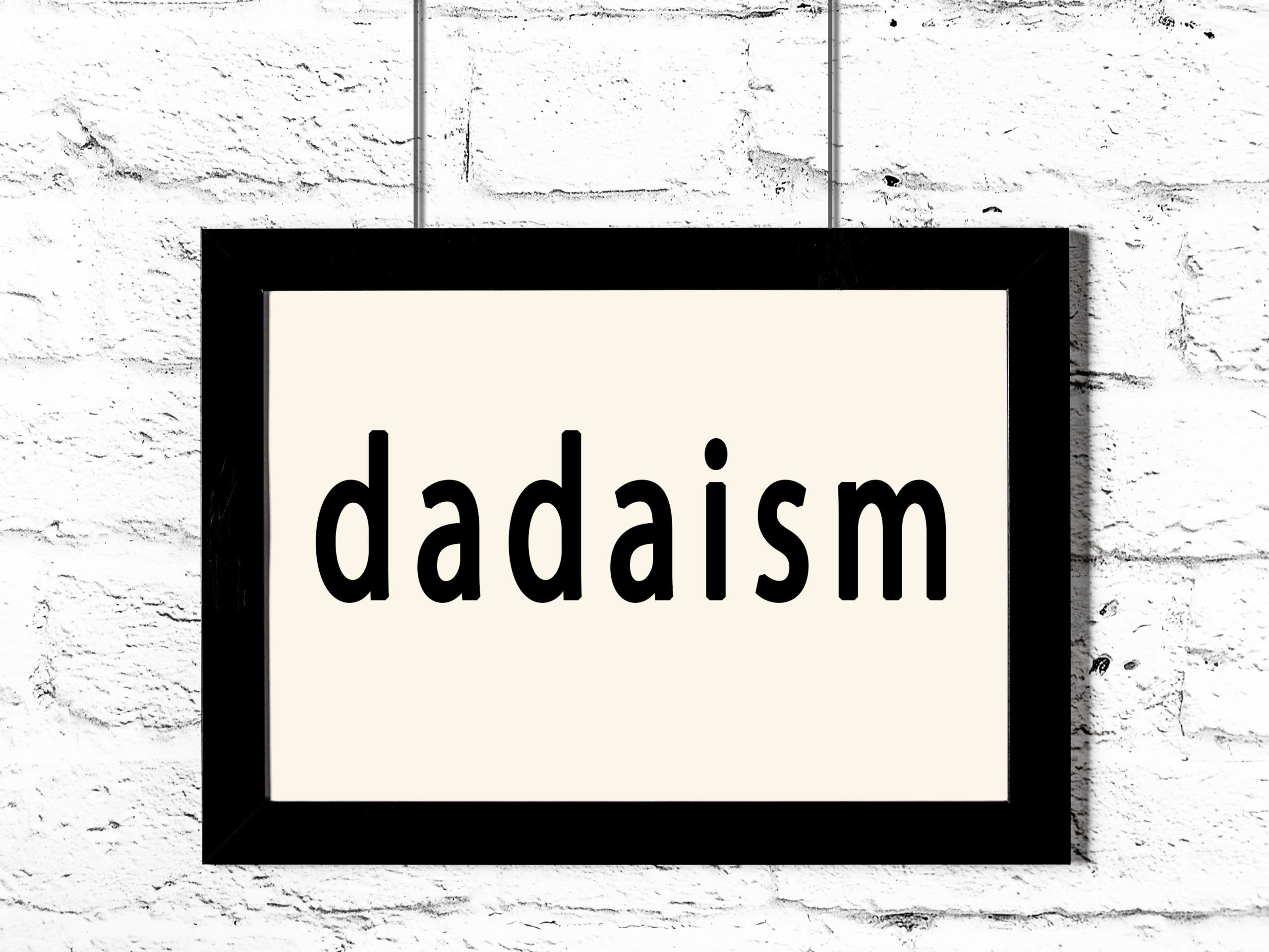 Black frame hanging on white brick wall with word dadaism.