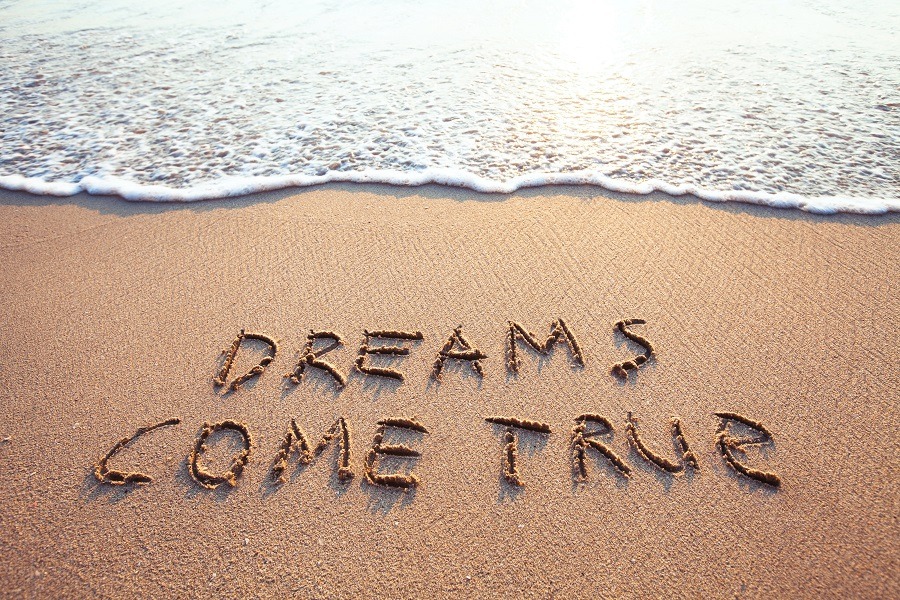 Dreams Come True written on the beach sand.