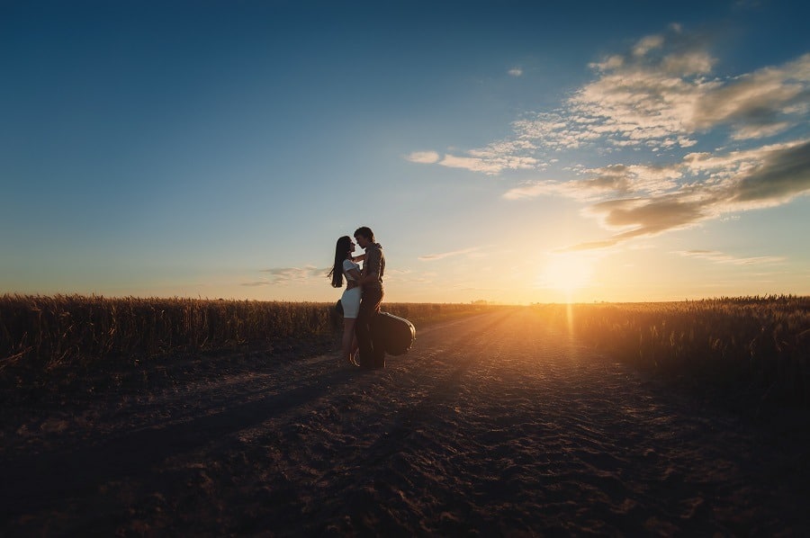 Young lovers stand and hug before a kiss against the background of the sunset.