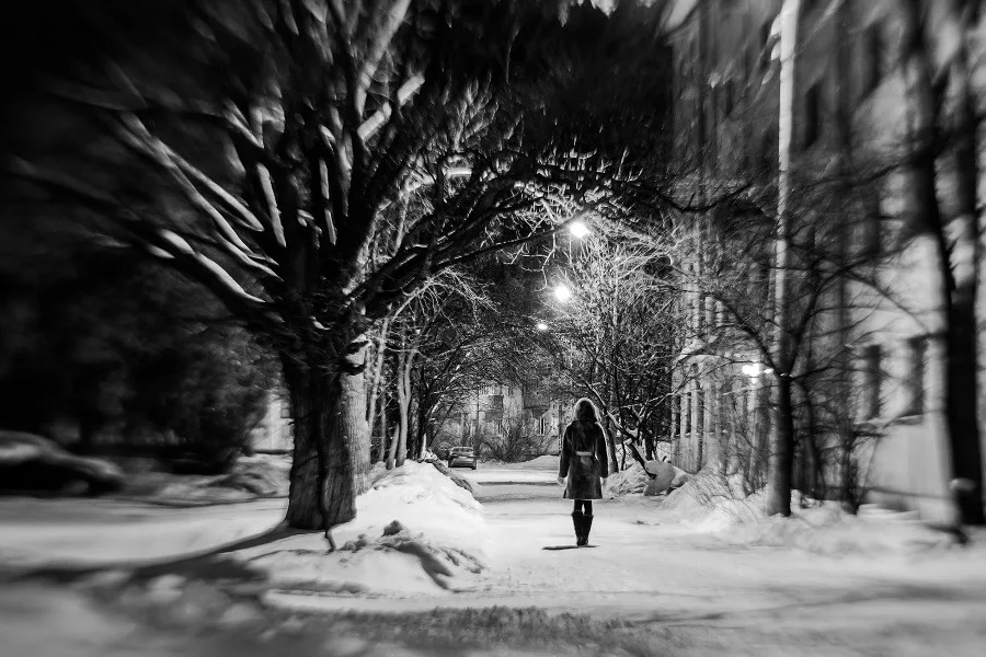 Lonely girl on the empty street in winter evening.