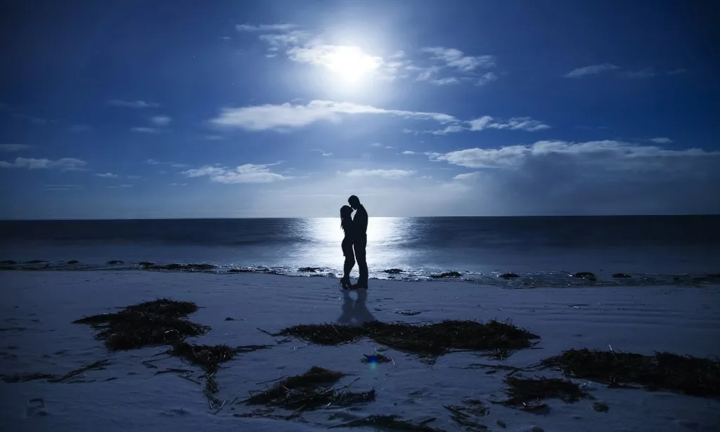 Silhouette kissing couple night at the seaside.