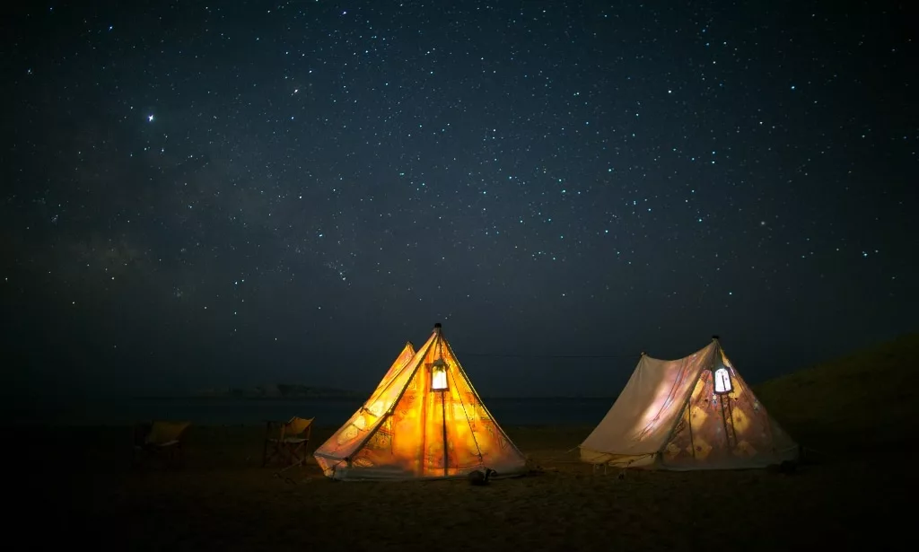Romantic lighted tents under the black starry sky.