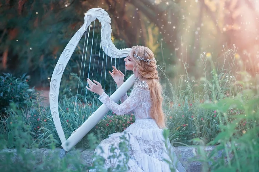 Mysterious wood nymph plays on white harp in fabulous place.