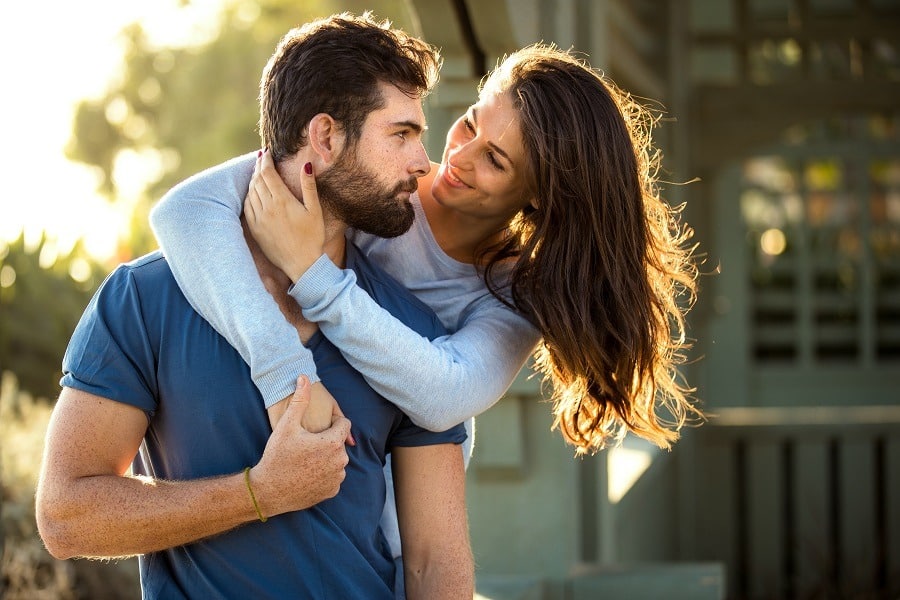 Handsome bearded man and brunette woman, strong athletic lovers embrace at the park.