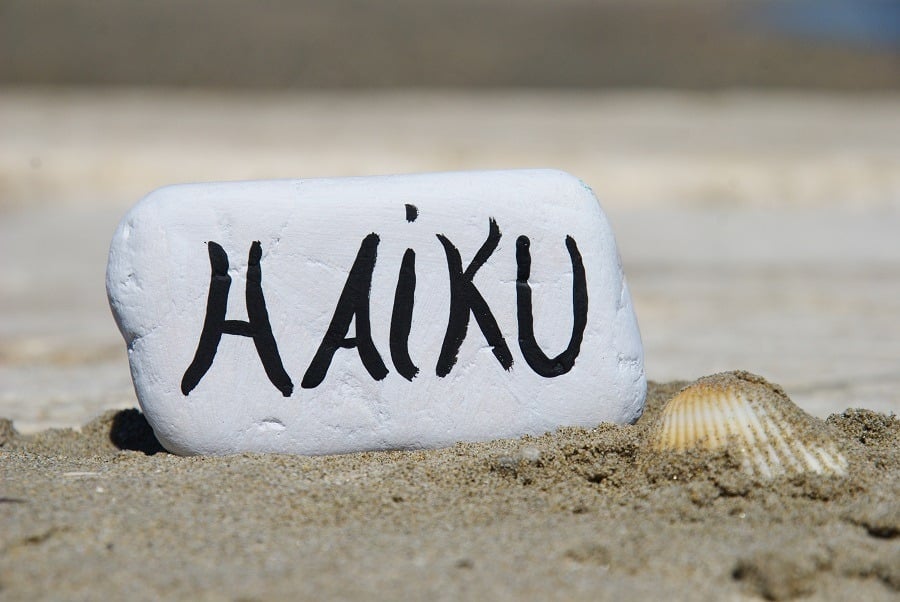 Haiku written on a piece of white stone on the beach.