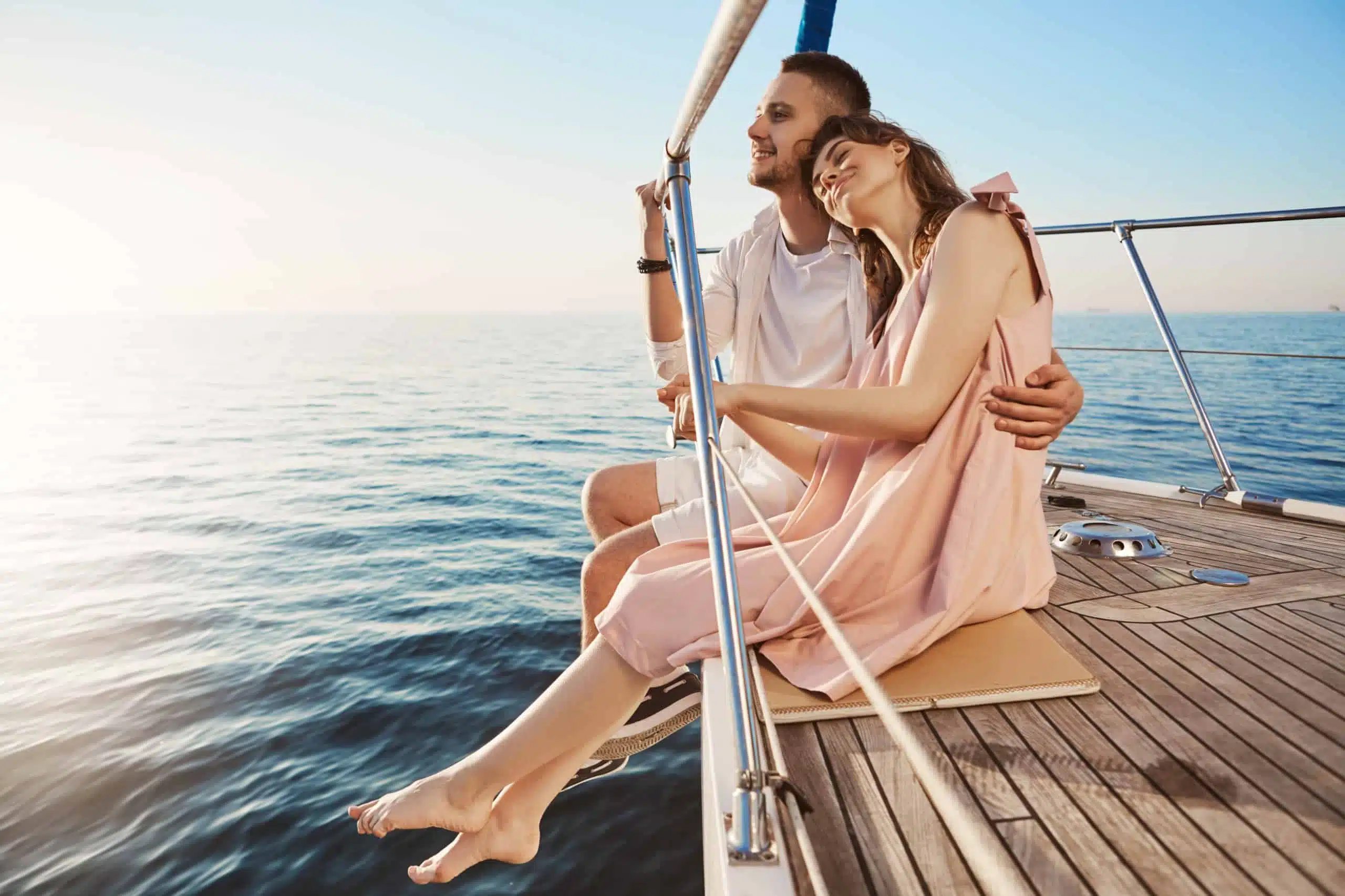 Happy beautiful couple sitting on side of yacht.
