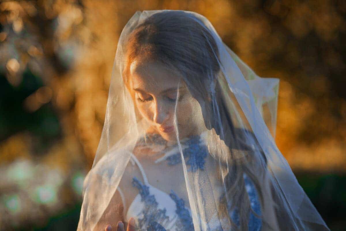 woman outdoor wearing a dress and a veil looking down
