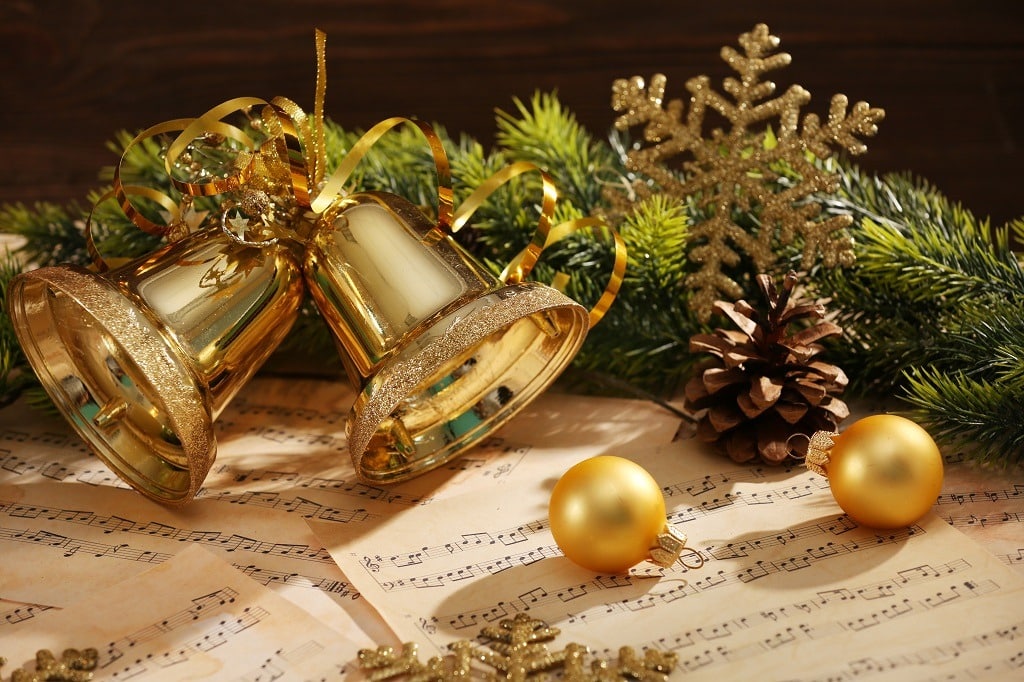 Golden Christmas bells and balls on music sheets.