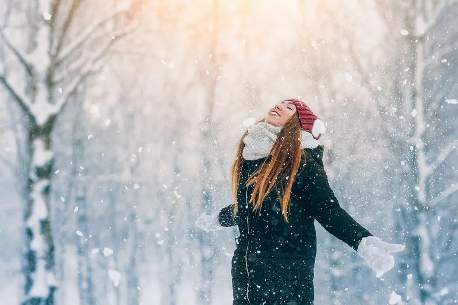 A girl having fun in winter, enjoying the snow falling from the sky.