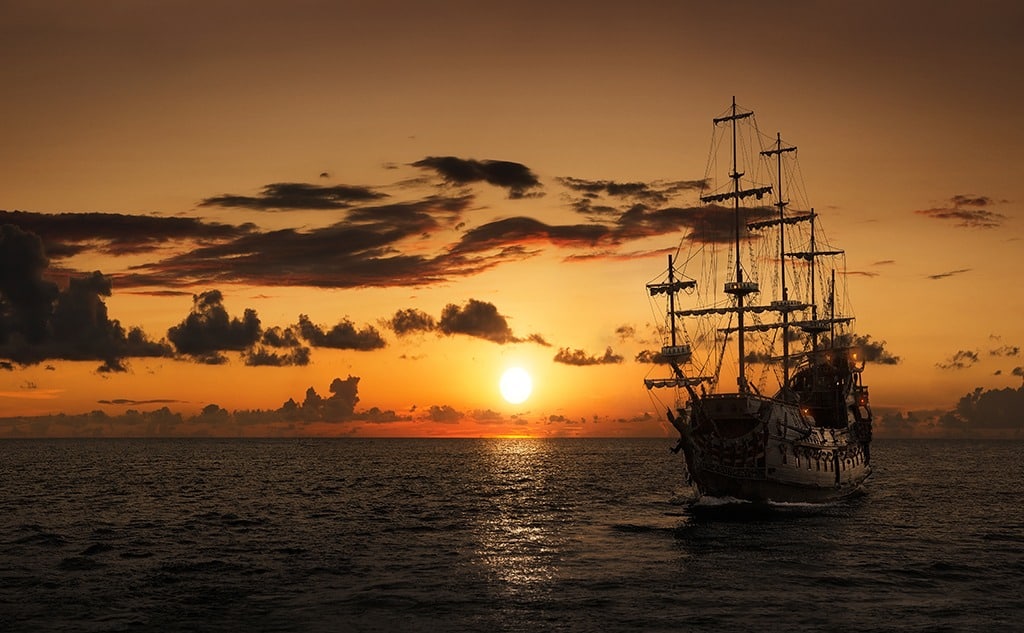 Pirate ship at the open sea at the sunset with copy space