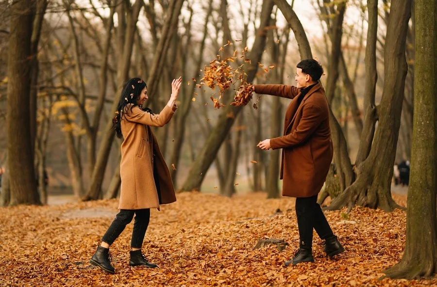 Young couple outdoors being playful on a beautiful autumn day in the forest. 