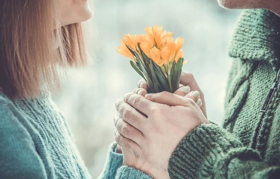 Loving couple holding hands each other with bouquet of beautiful yellow flowers. 