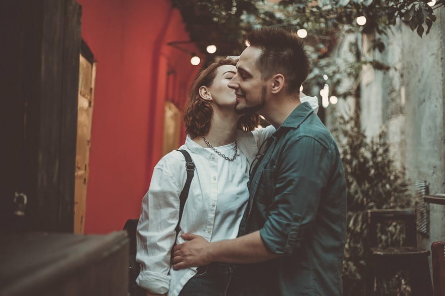 Cheerful couple in love kissing in a city street.
