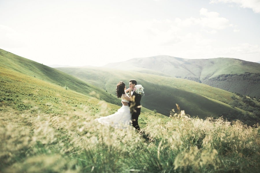Beautiful wedding couple in love on green rolling hills.