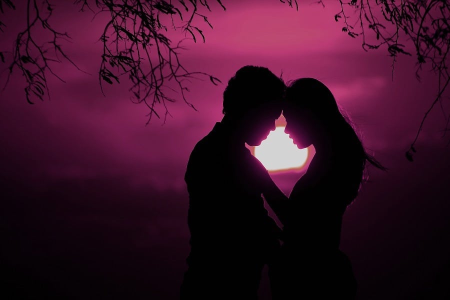Silhouette of lovers in purple sunset.