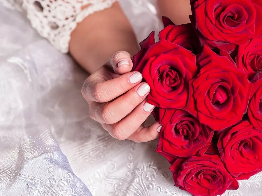 Bride with bouquet of red roses.