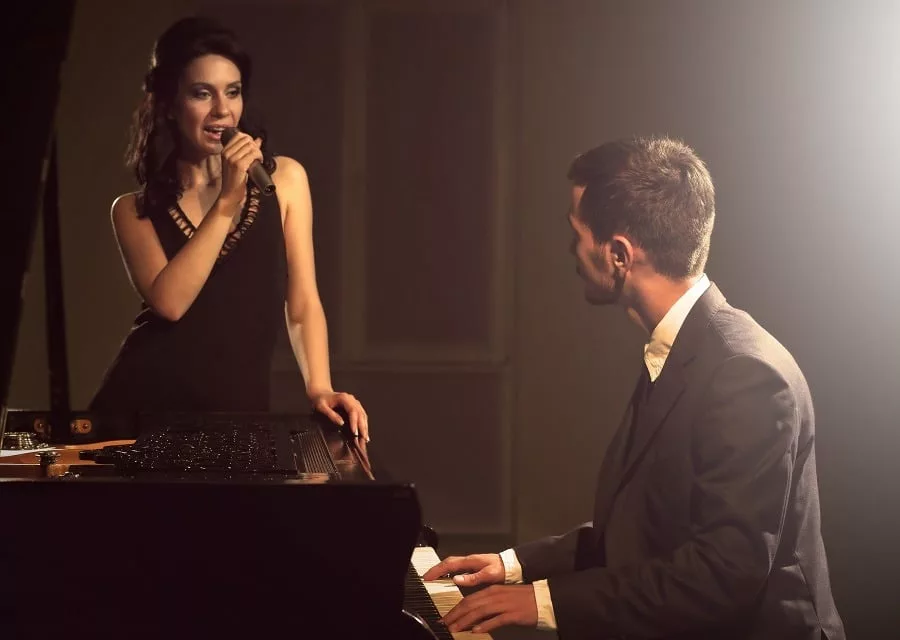 Woman singing man on the piano looking at woman in love.
