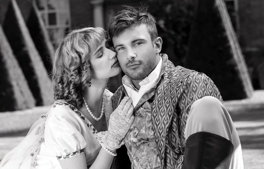 Young lovers dressed in vintage clothing the woman kisses him on cheek.