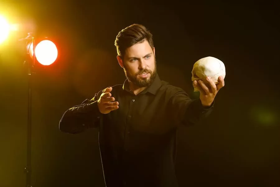 Male actor with human skull on stage.