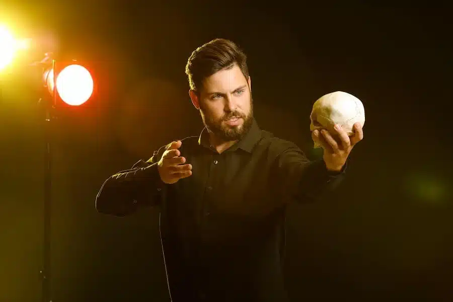 Male actor with human skull on stage.
