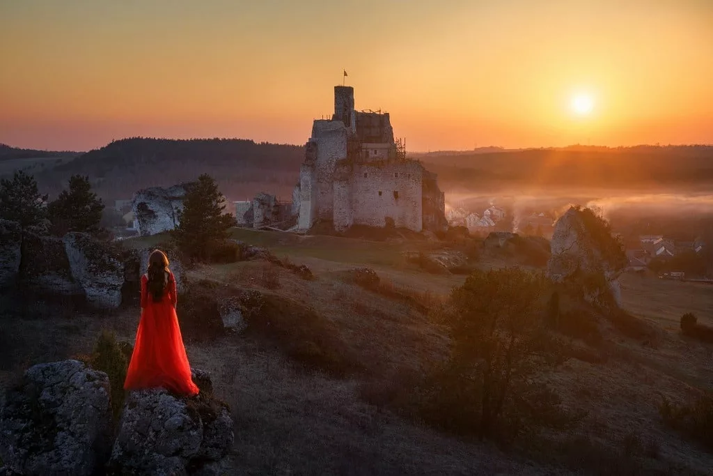Woman in red dress looking at the castle from afar.
