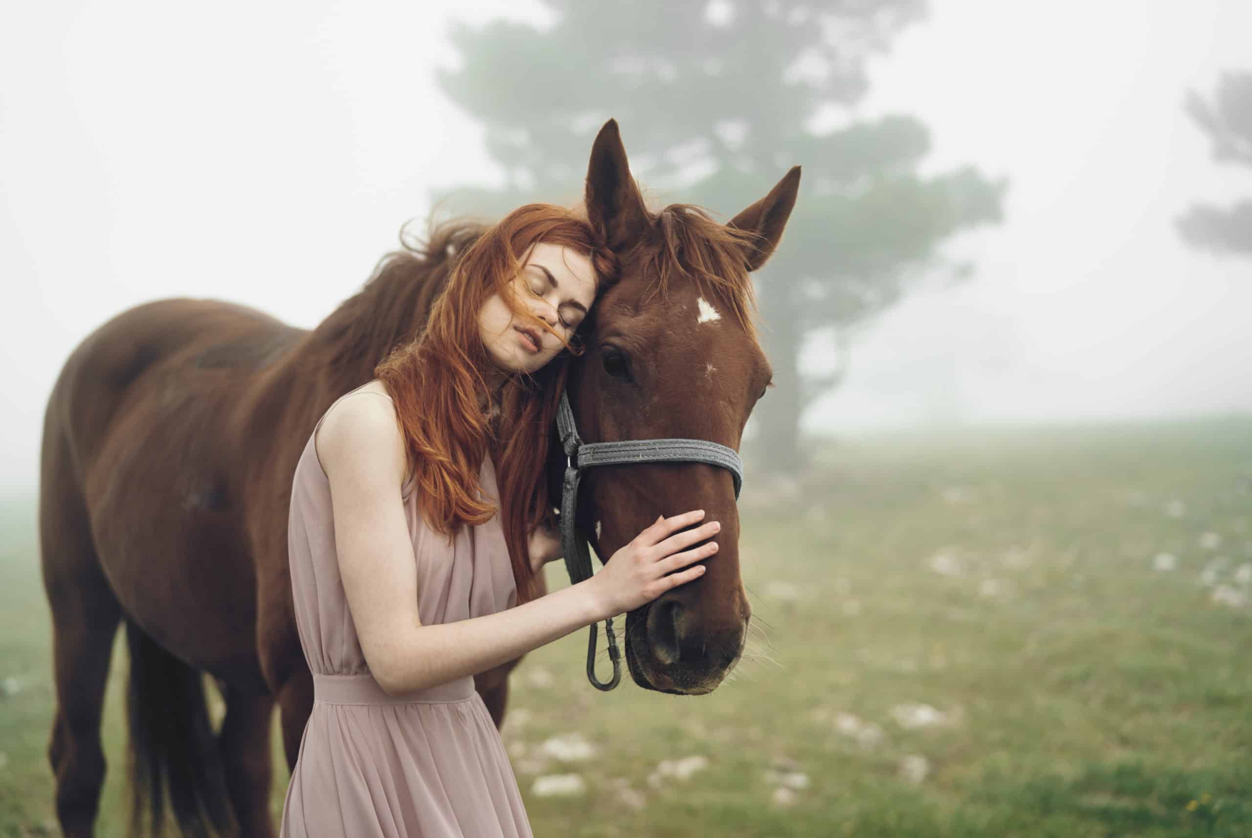 Beautiful young woman walking in the misty mountains with her horse.