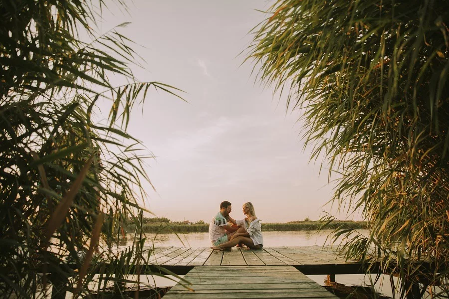 Romantic couple sitting on the wooden pier on the lake.