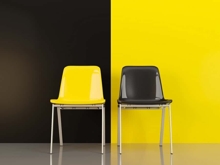 A yellow and a black chair contrasting the black and yellow wall.