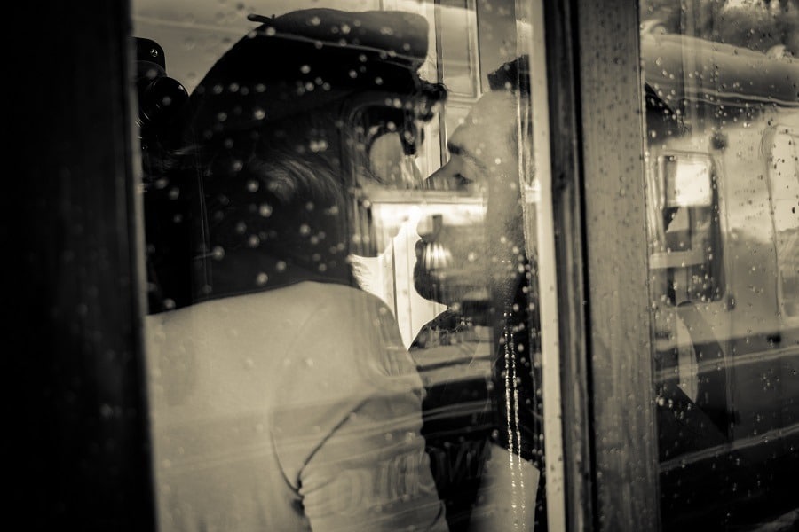 Secret lovers kissing and holding each other passionately in phone booth.
