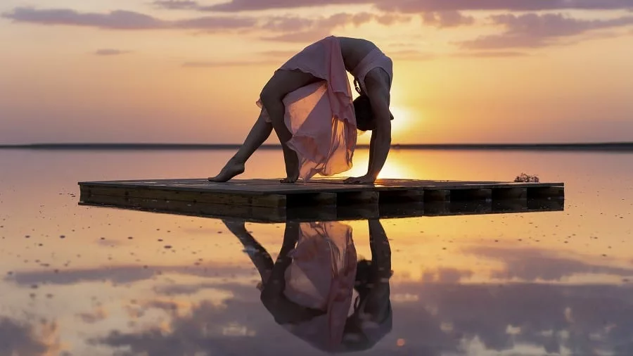 Graceful gymnast against the background of a pink sunset.