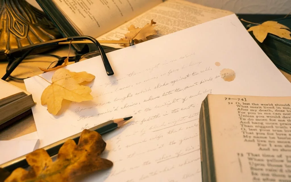Aesthetic desk with Shakespeare sonnets surrounded by fallen autumn leaves.