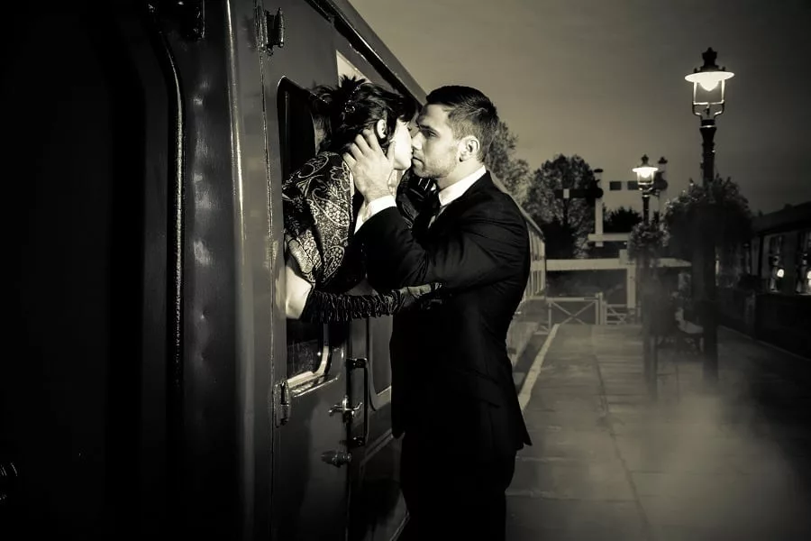 Passionate couple embracing and kissing on railway station platform as train is about to depart.