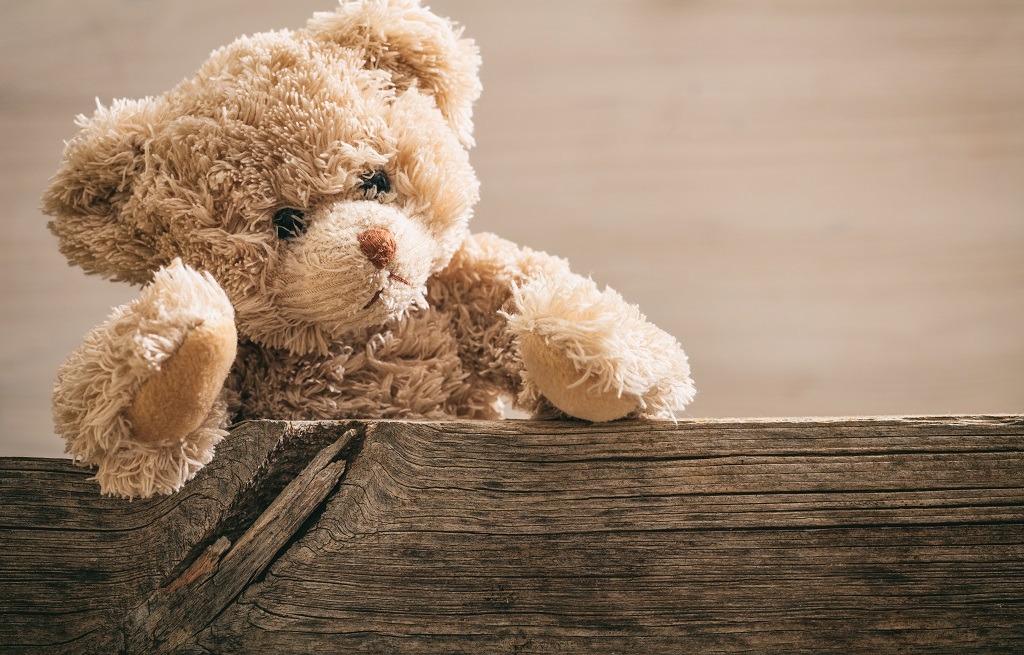 Angry-looking Teddy bear on wooden background.