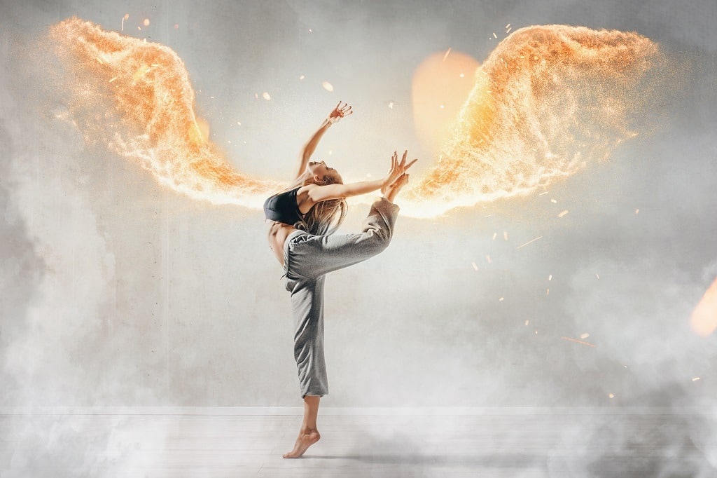 Fit woman has fire wings while dancing.
