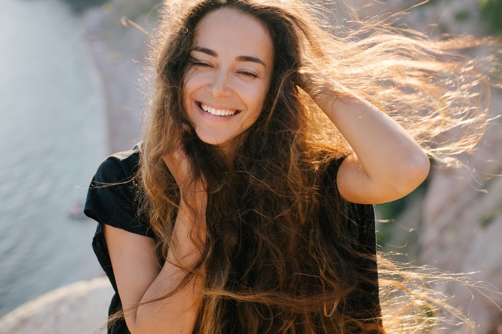 Happy woman with long hair on top of the mountain.