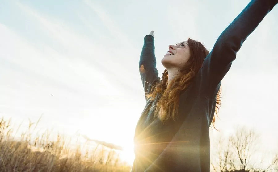 Young woman outdoor at sunrise expressing joy, freedom in success.