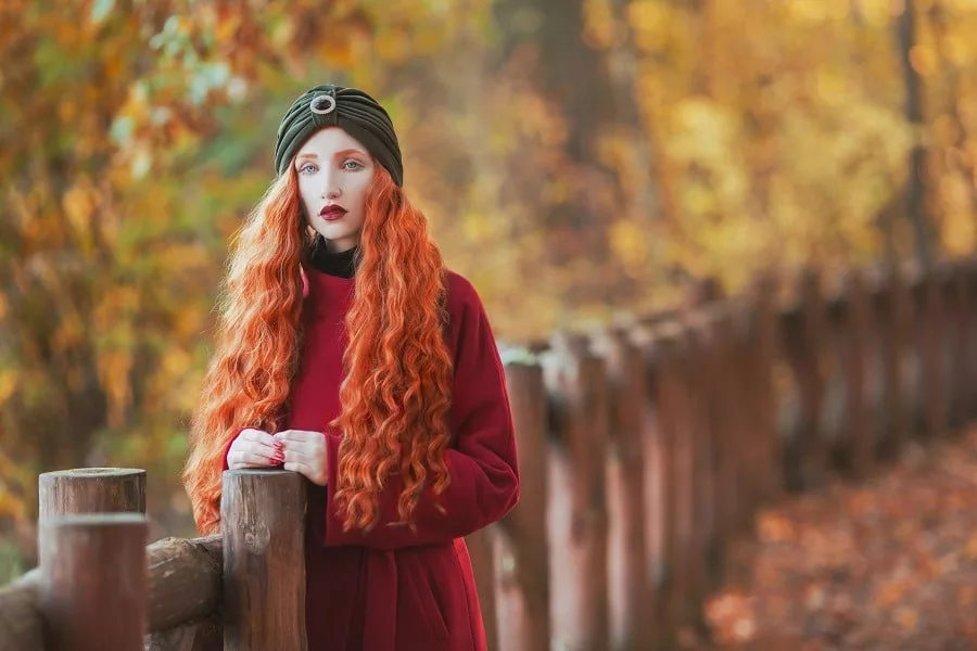 Beautiful long-haired redhead lady on picturesque autumn background.