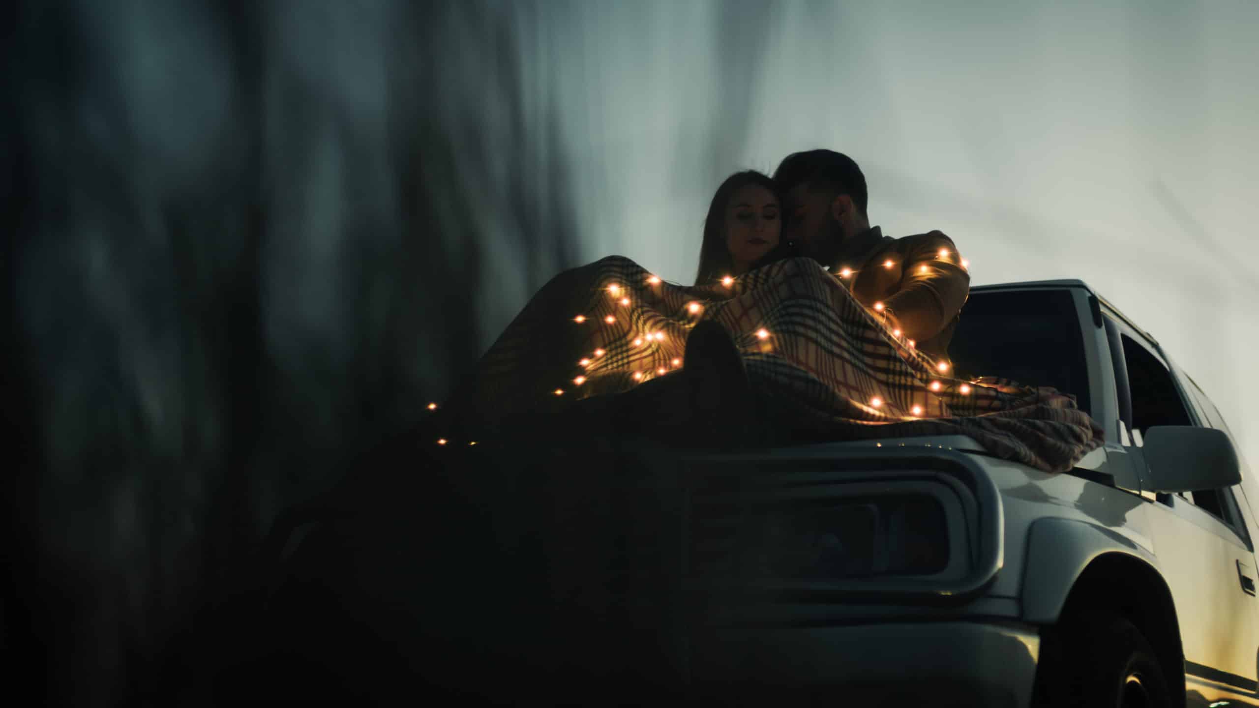Romantic couple in love camping out on their truck at night.