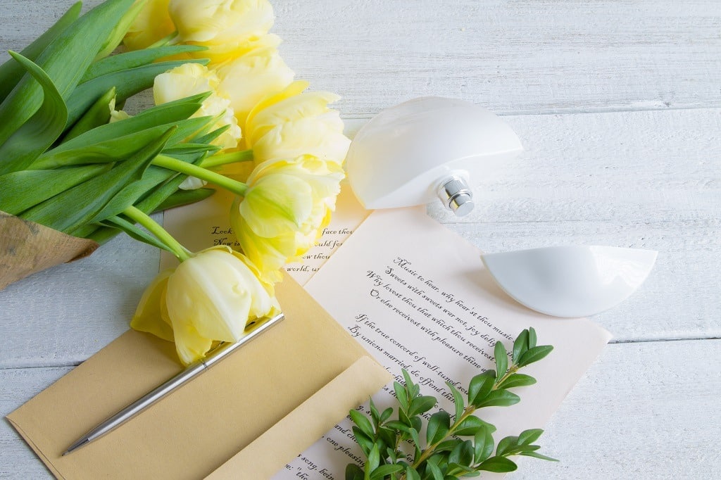 A bouquet of yellow tulips, on a white wooden background with Shakespeare poems.