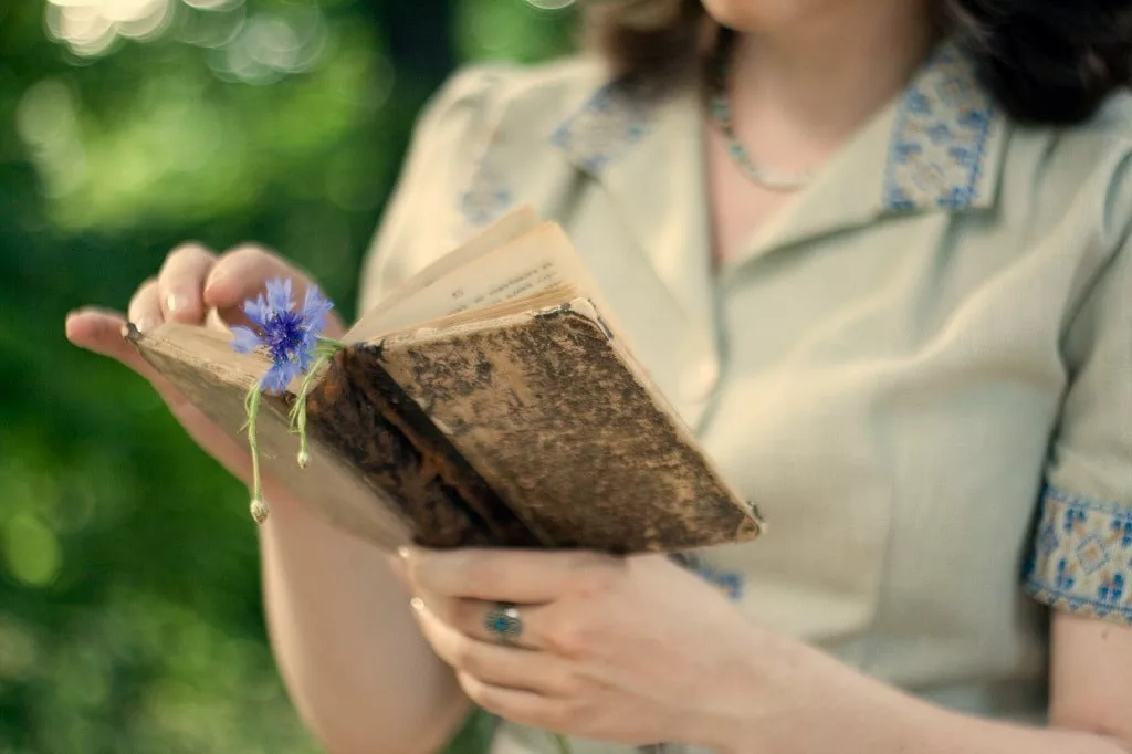 A young girl in a vintage dress holding old book.