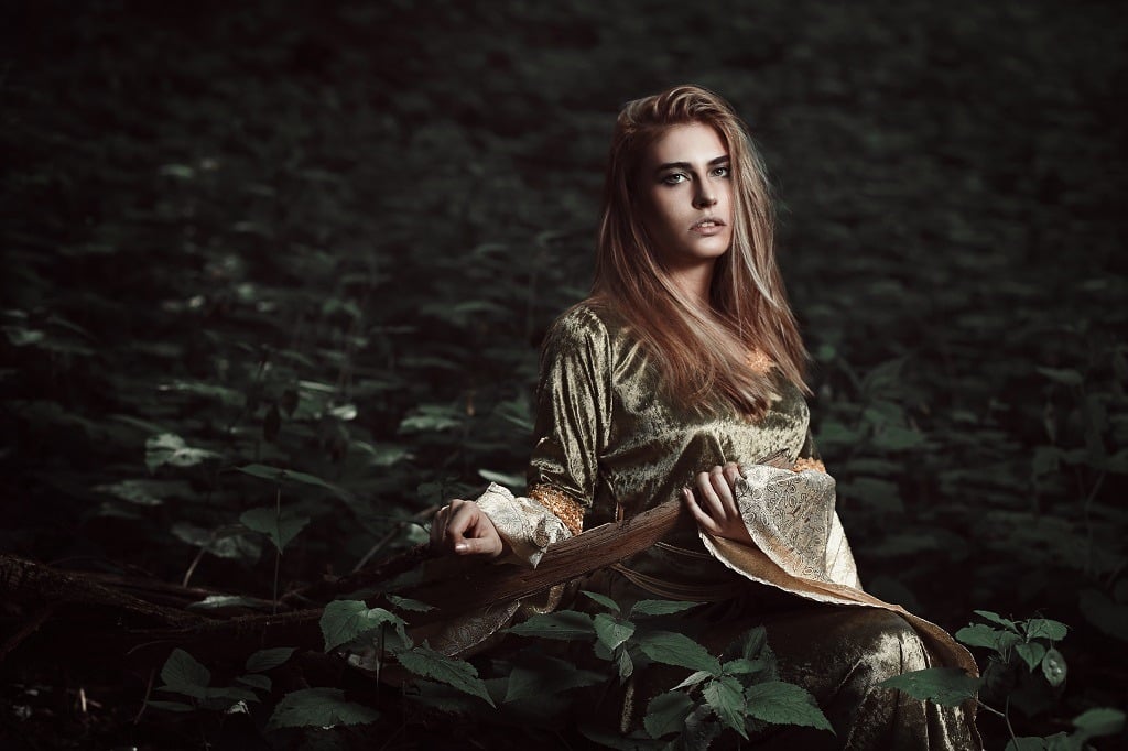 Melancholic elfin girl in magical forest.