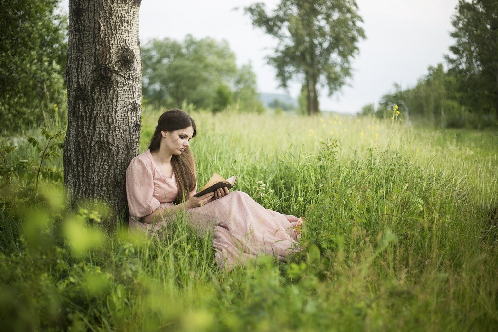 Young woman reading a book in nature