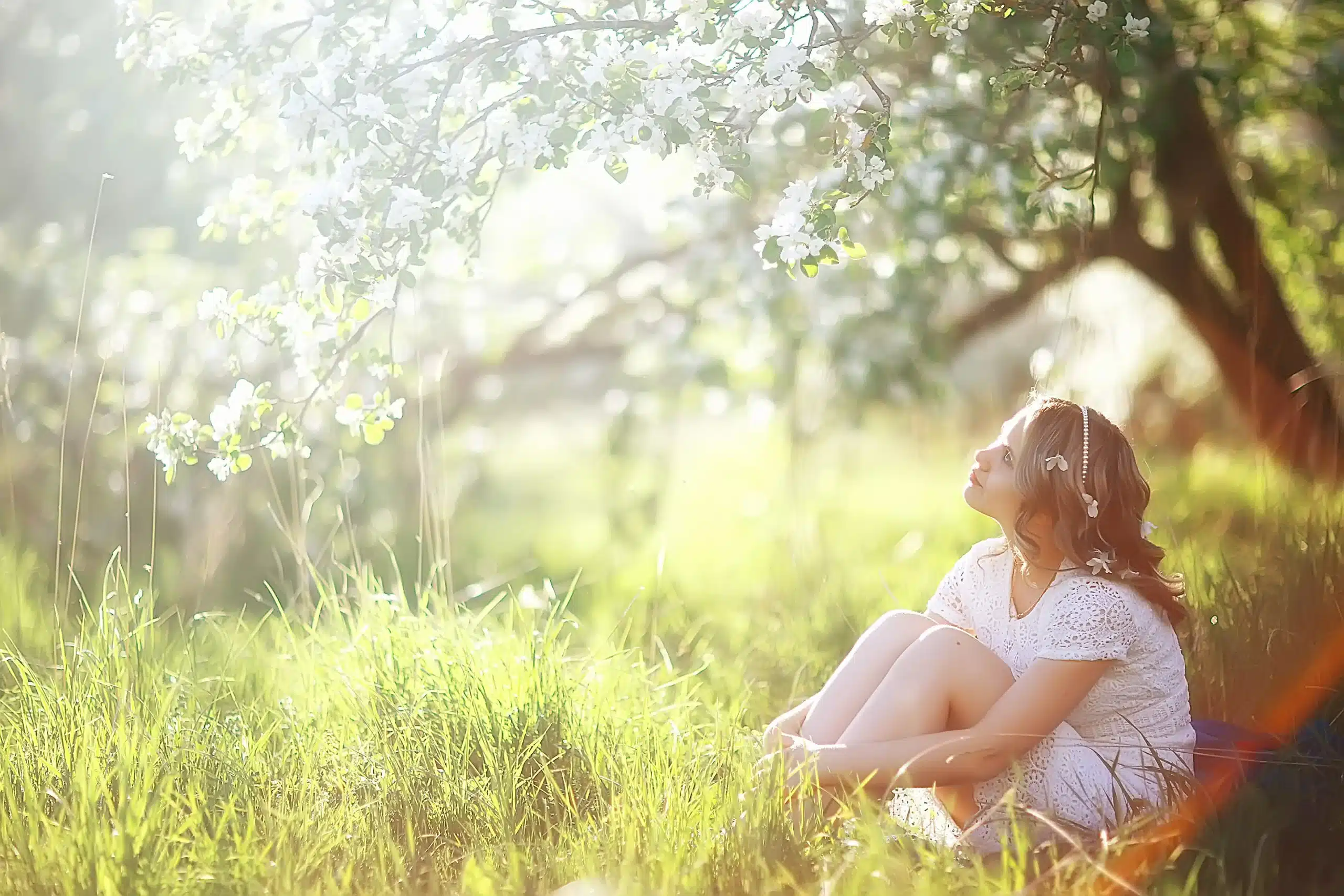 Young woman enjoys spring apple flowers in nature.