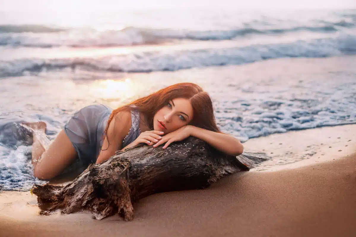 The transformation of a mermaid. A woman in a wet dress lies on the beach.