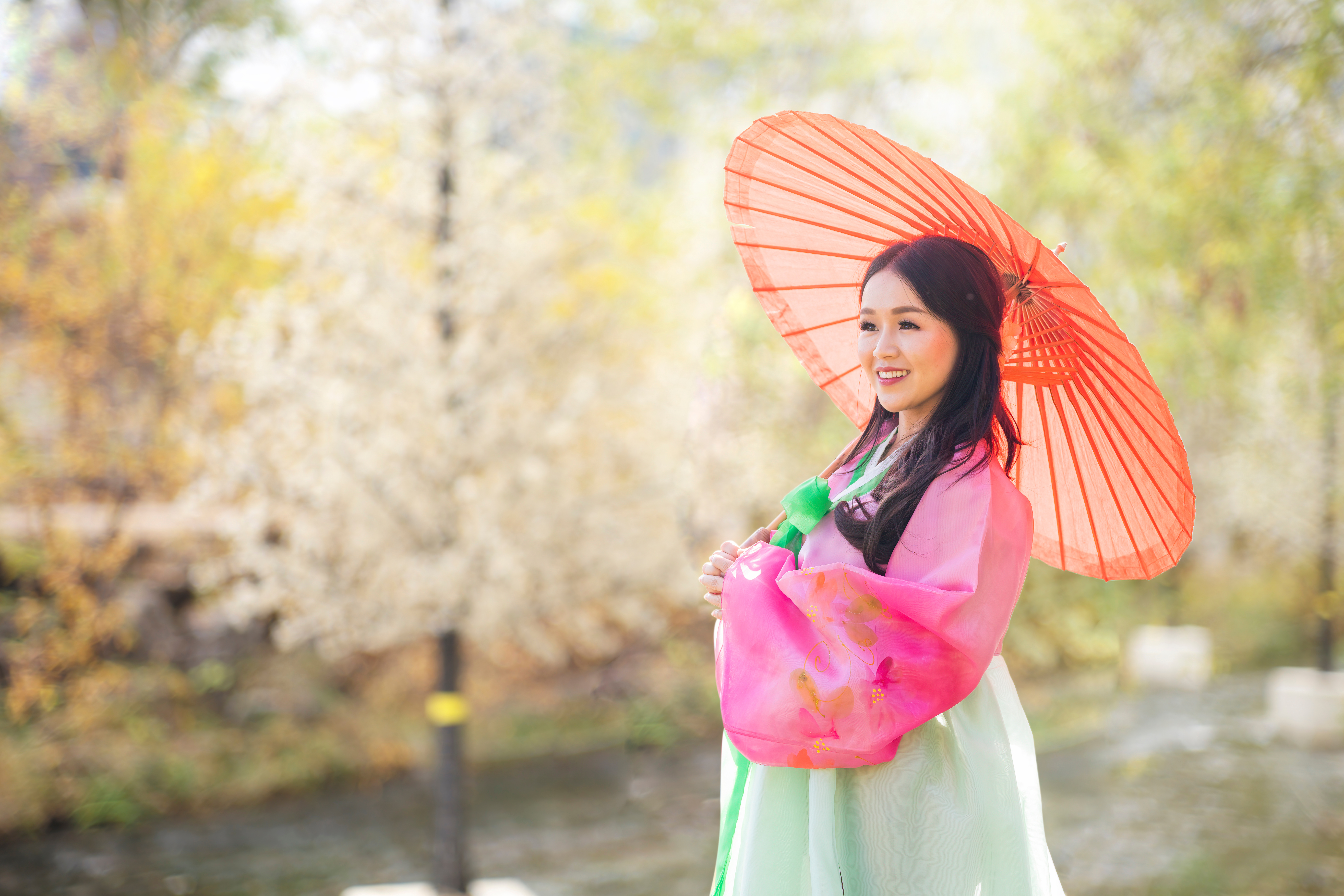 Korean girl wearing a hanbok and holding a red umbrella